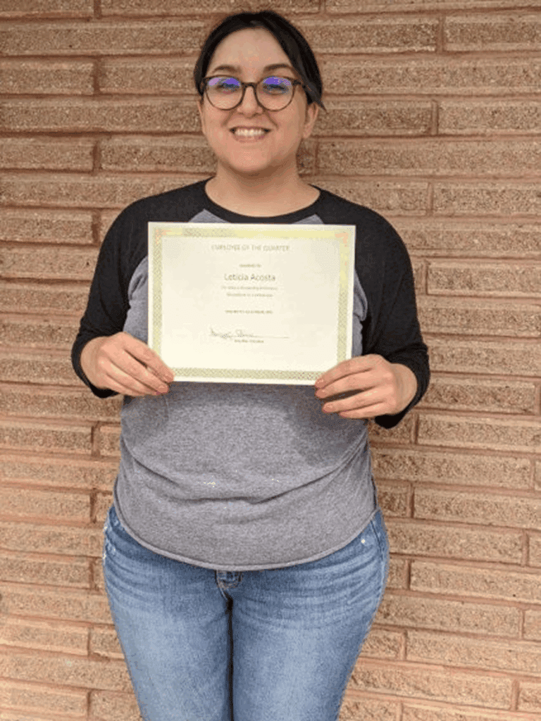 Person holding a certificate against brick wall.
