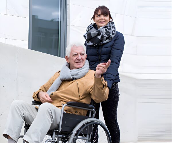 Older man in wheelchair with caregiver outside