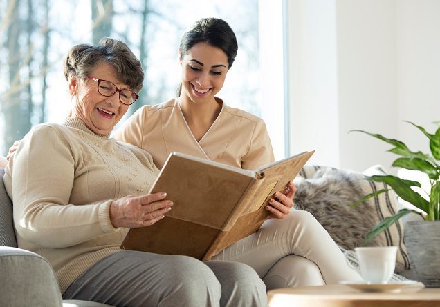 Elderly woman and caregiver reading together