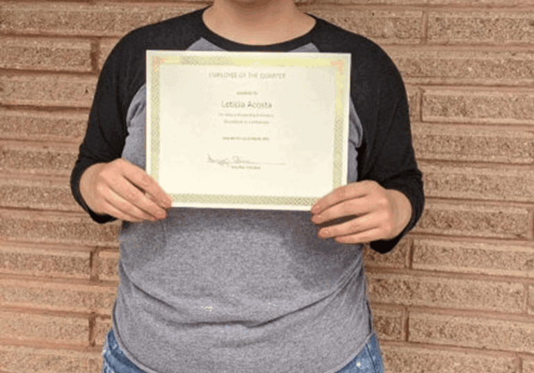 Person holding a certificate against brick wall.
