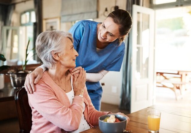 Caregiver comforting elderly woman at home