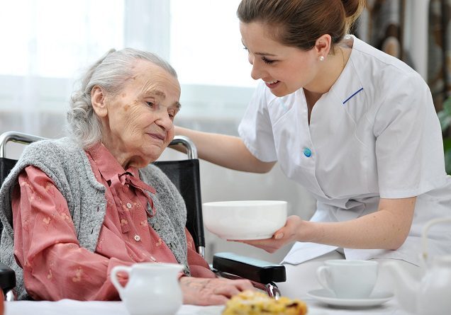 Nurse helping elderly woman in wheelchair